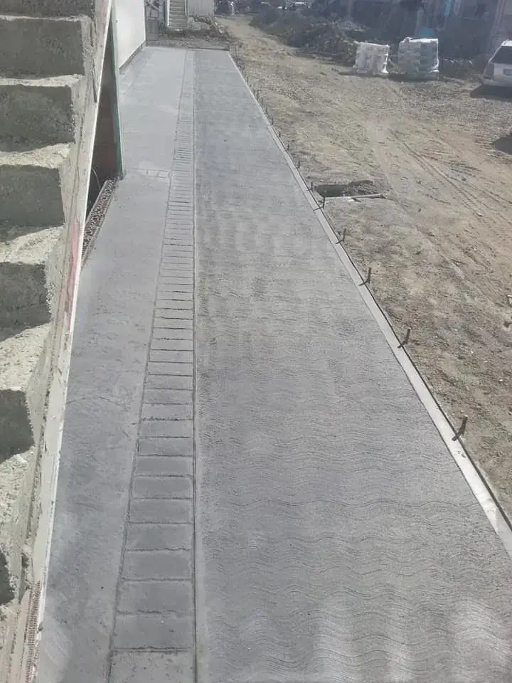 Trotuar din beton periat gri realizat lângă casă cu finisaj modern și margini precise de Rbeton